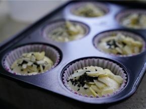 然后将蛋糕糊挤在纸托里，再用杏仁片及熟芝麻点缀。