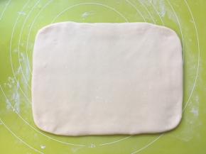 揉面垫上撒点干粉将白色面团擀成长方形，大小为小号保鲜袋的大小，之后包裹上油纸，装入保鲜袋入冰箱冷冻 
