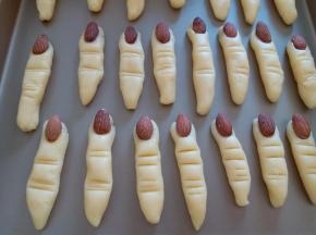 把面团分每个10到14克，我是随意分的，毕竟每个手指也不一样大小，杏仁沾上的蛋液沾在饼干的前端，做手指的指甲。再用刮板刻出手指的皱纹