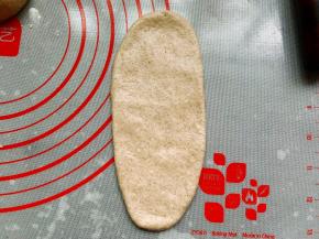 将松弛好的面团擀成椭圆形，拍掉两边大气泡。