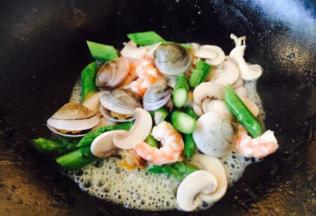 放入鲜虾仁、青蛤、芦笋，翻炒均匀。
