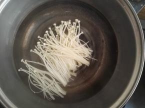 2、开水锅中加入一点盐，洗净的金针菇放入锅中焯一下捞出晾凉。