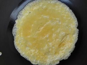 5、锅中倒入食用油，将蛋液倒入锅中，慢慢转动锅，将蛋液摊开，当蛋液的边缘翘起来时，将蛋皮掀起翻面，另一面煎好后取出。