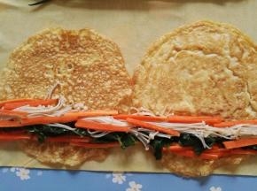 7、将豆皮在面板上摊开，蛋皮置于豆皮上，芹菜叶、胡萝卜、金针菇排好放在蛋皮上。