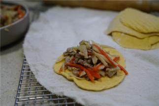 醒好的面团重新揉搓好，擀至面皮薄圆，将炒好的馅料包制在里面。