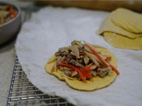 醒好的面团重新揉搓好，擀至面皮薄圆，将炒好的馅料包制在里面。