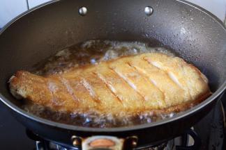 当鱼的一面煎至金黄色时翻过来再煎另一面，两面都煎至金黄色就OK了。
温馨提示，当把鱼刚刚放到锅里后千万不要急于翻动，如果翻动了，肯定会粘锅的，因为油很热，鱼和铲子都是凉的，热油一下子就会“抱住”铲子和鱼，肯定会粘锅。
那么我们什么时候才能翻动鱼呢，1，中火煎制至少2分钟后才能翻动。2，还有就是被煎鱼的那面两边会有明显的金黄色才可以翻动。3，再有就是当离火晃动锅时，鱼可随意在锅里滑动也可以翻动。建议初学者用第2种方法判断。 
温馨提示，因为鱼比较大，在翻动鱼时请用两把铲子翻动。