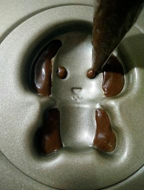 裱花袋剪小口，将可可面糊挤入小狗耳朵和眼睛部位。