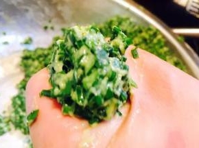 用手抓住一团韭菜糊，从虎口挤出直径约4～5厘米左右的小圆子，放入油锅中。