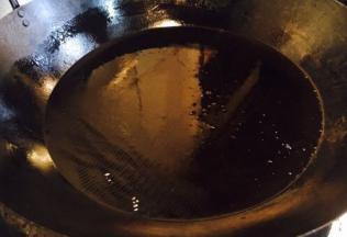 开大火置锅，锅热后放入大量的油，当油的表面有波纹动时，改中小火，准备炸小丸子。