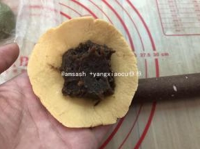 用擀面杖擀出中间厚边缘薄的面皮就可以，实在不会擀，边缘用手捏薄也完全可行，擀好的面皮依然用保鲜膜盖住，取一张包子皮码上适量的豆沙