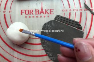 然后把大的面团分成5等份，用保鲜膜盖，以防面皮干燥，取出黑色面团擀成薄片，用刮板切成细丝条状，取出一个白面团，表面刷上水或牛奶，然后把细丝贴上做成一个网状，然后再用手指轻轻按压一下