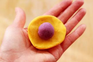 用手摁扁后，把静置好的紫薯揉成圆球放到南瓜面皮上面。