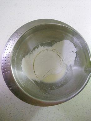玉米油和牛奶倒入容器中，用手动打蛋器搅拌均匀，充分乳化看不到油花，筛入低筋面粉与玉米淀粉，用手动打蛋器搅拌，混合至无干粉状。