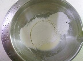 玉米油和牛奶倒入容器中，用手动打蛋器搅拌均匀，充分乳化看不到油花，筛入低筋面粉与玉米淀粉，用手动打蛋器搅拌，混合至无干粉状。