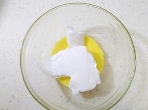 取出25克蛋黄倒入干净的容器，分两次加入35克蛋白霜翻拌均匀。