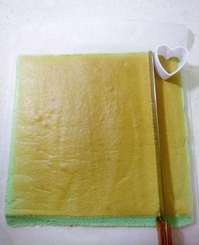 把两段边斜角切掉，用锯齿刀切出心形模具宽度的一条蛋糕卷备用（做小象耳朵）。