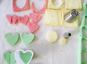 纸杯蛋糕用锯齿刀分层，粉色用小一圈的心形刻模，原色戚风用裱花嘴刻出大小圆形备用（小象帽子），用剩余的边角料剪出小象鼻子。。