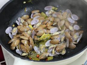 把花蛤倒入炒锅中，翻拌几下。