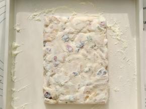 折叠均匀后放入烤盘里整形。可以借助刮板压实，但不要压的太薄，3cm左右的厚度。趁余温在雪花酥表面撒一层奶粉。