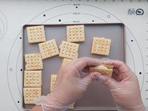 用刮刀挖一点粘在两片苏打饼干中间。或者带上一次性手套直接用手把炒好的棉花糖分成小份放在苏打饼干上，两片夹好就OK了。