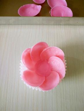 轻捏勺子轻松脱模，在纸托中间挤入少量巧克力，取花瓣竖起来摆放整齐待凝固。