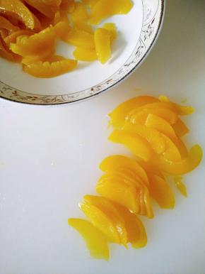 取出黄桃罐头用厨房纸吸一下水分，切成薄片备用。