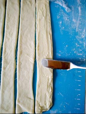 用刀切成长条面片，在面团上抹上杏仁奶油馅，别抹太多不好卷。