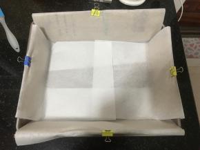 19. 准备蛋糕烤盘，找个纸箱子，剪出几个可以放进烤盘四边的纸片，纸板高出一部分，里面铺油纸，油纸光面在外，毛面在内侧不然影响蛋糕爬升，加入硬纸板的作用是，一部分辅助蛋糕糊量多长高，主要是防止四周边缘上色，符合古早味的外形。