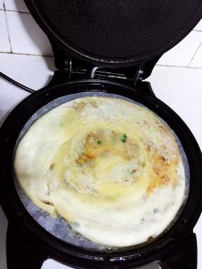 电饼铛预热后，倒入少许油。把擀好的饼放进去。