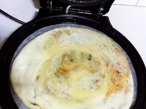 电饼铛预热后，倒入少许油。把擀好的饼放进去。