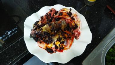 腌好的鱼头洗干净放在碟子里，将3勺老干妈均匀铺在鱼头上，洒上适量蒜盐、少许糖