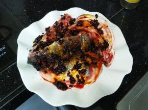 腌好的鱼头洗干净放在碟子里，将3勺老干妈均匀铺在鱼头上，洒上适量蒜盐、少许糖