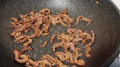 热锅热油下牛肉丝爆炒变色。