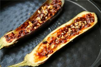 烤软之后的茄子，从中间划两刀，这样更方便入味。茄子上面刷一层薄油，再均匀铺上拌好的韩式蒜末酱料。