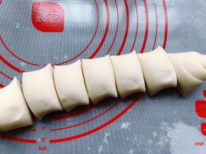 取出发酵好的面团，用刮板分成3份，分别将这三块面团擀成长方形的面片，然后在面片表面喷上少许水，卷成长条形，并用刮板分割成大小差不多的小剂子，500克面粉我大概做了23个包子。