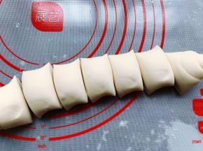 取出发酵好的面团，用刮板分成3份，分别将这三块面团擀成长方形的面片，然后在面片表面喷上少许水，卷成长条形，并用刮板分割成大小差不多的小剂子，500克面粉我大概做了23个包子。