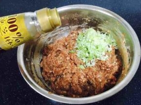 最后放入葱花，在葱花上放约20g左右的香油，先用香油把葱花拌匀，再将葱花与肉馅充分调匀，即朝一个方向搅拌均匀，大约搅拌100下左右。 先用油裹住葱花的目的是防止葱汁外溢，造成肉馅葱味过重。猪肉馅调好了备用。
