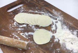 把小圆剂子压平，擀成饺子皮，擀饺子要中间厚，周边薄。