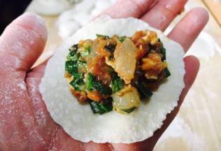 往饺子皮上放适量的饺子馅。