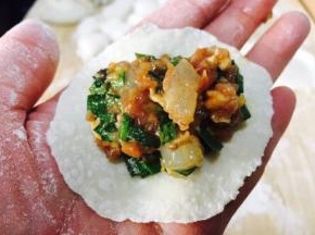 往饺子皮上放适量的饺子馅。