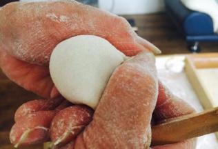 先将饺子皮对折，中间捏紧，然后用双手的拇指和食指将饺子皮的边向中间轻轻挤压。