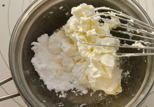 趁面团一发我们来制作奶酪馅。把奶酪与糖粉放入碗中，把碗坐在热水上。用手动打蛋器搅打至奶酪软化顺滑。
