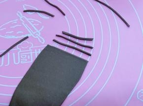 可可面团用擀面杖擀成面皮，再切出细条，做眉毛与嘴巴！