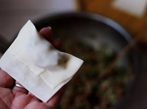 把上面的皮压在中间，用手把馄饨皮的周围捏紧后。