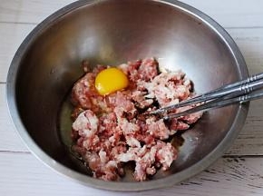 猪肉馅里加入生抽和料酒，然后打散一枚鸡蛋。