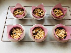 将面糊放入到纸杯中，撒上泡软的麦片