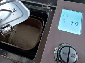 将面包桶放入到东菱JD08面包机里，盖上面包桶的防溅盖，防止和面的时候面粉飞溅出来，弄脏面包机。选择面包机的和面程序10分钟
