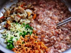 在搅拌好的肉馅里，加入金钩海米，扇贝肉和葱姜末，继续用筷子顺时针方向搅拌均匀。