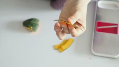 接下来来处理一下蛋糕卷表面的南瓜片，这里我们选用的是带绿皮的南瓜，像贝贝南瓜、板栗南瓜都是可以，主要注意擦片的时候我们要连皮一起擦成薄片，大约1.5mm厚度，这样的南瓜片烤好以后才有韧性，方便弯折，不易造成蛋糕体断裂开来